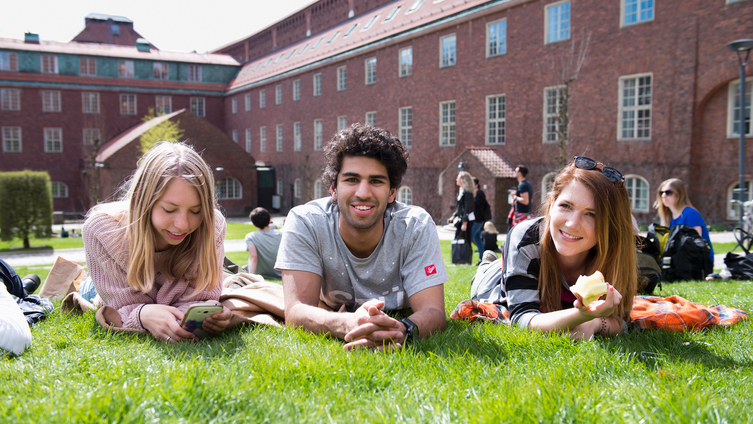 Studenter ligger på gräsmatta utanför ett universitet. Foto: Eva Dalin