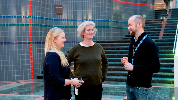 Tre personer pratar med varandra i en trappa.
