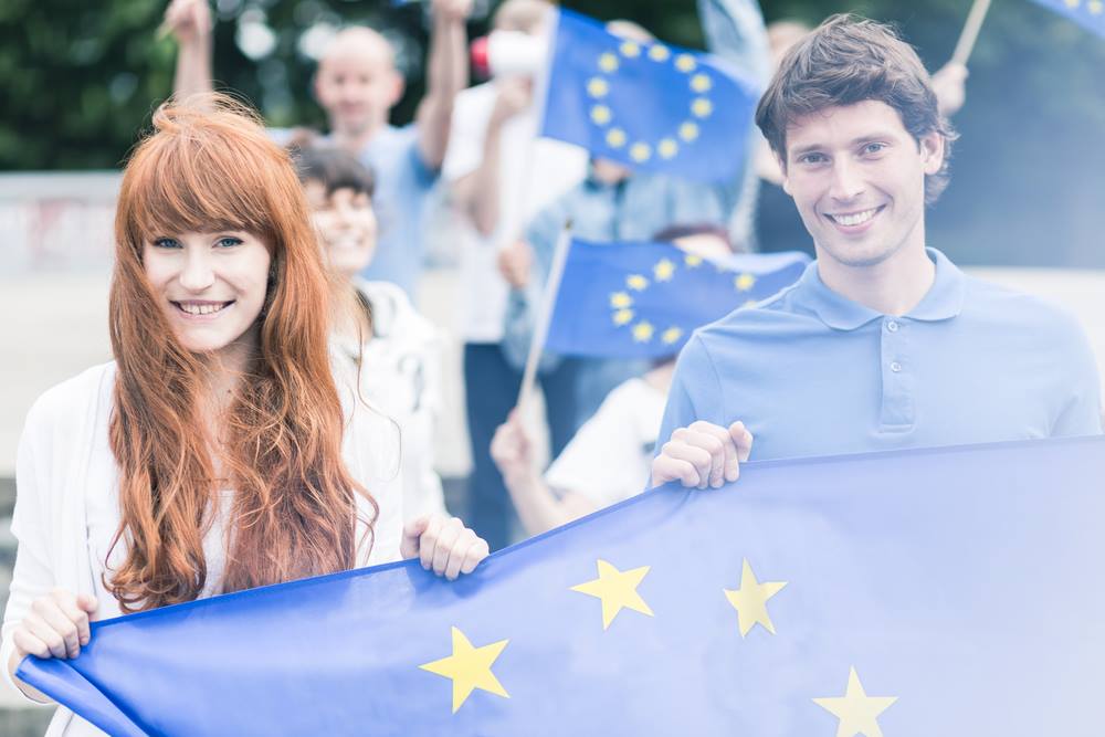 Två personer som håller i en EU-flagga