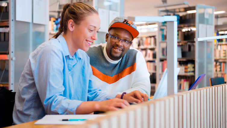 Två studenter studerar på bibliotek.