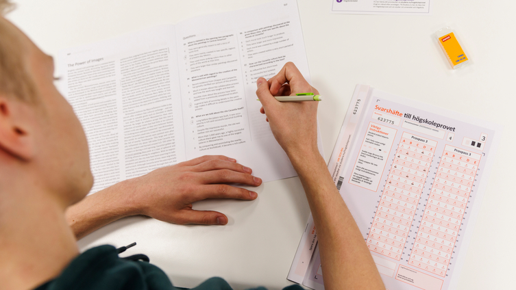 Ung student skriver högskoleprovet i provsal.