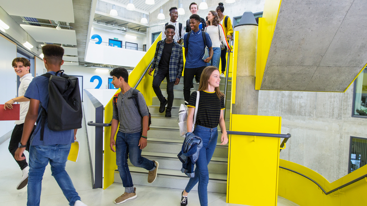 Tio studenter går nerför en universitetstrappa. Foto: johner.se/Caiaimage