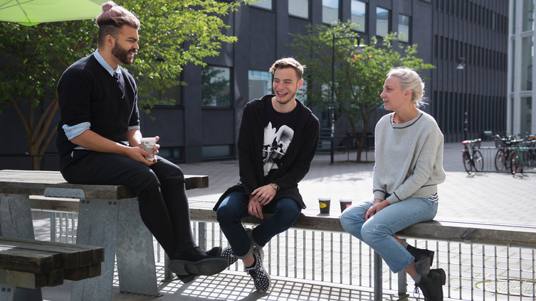 Tre studenter sitter och samtalar utanför sin högskola. Foto: Eva Dalin