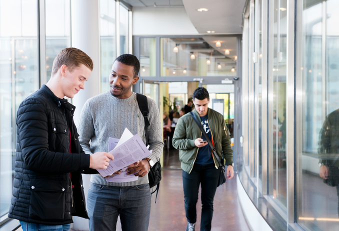 Tre manliga studenter i en korridor