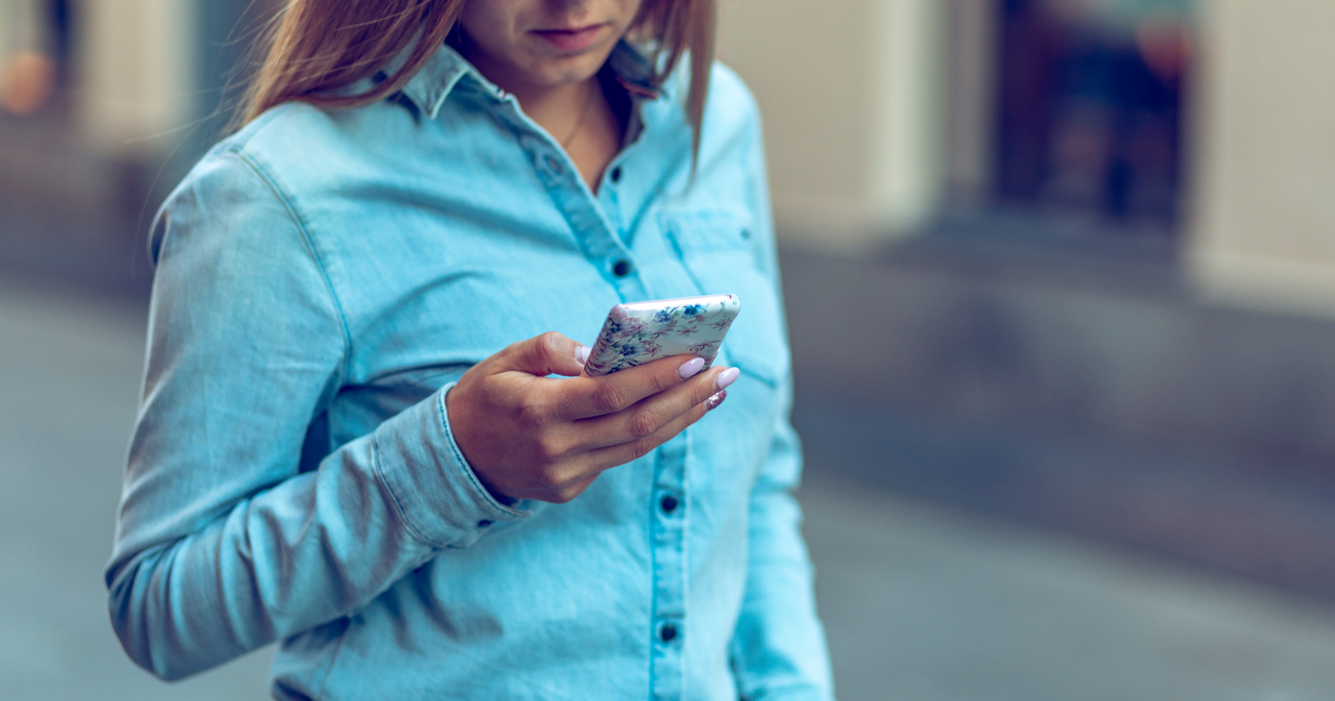 Kvinna i jeansskjorta tittar i mobil-fb-tw-li-content-1200x630px.jpg